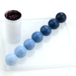 Foto zeigt einen Behaelter gefuellt mit Pastenfarbe indigoblau und Fondantkugeln mit den moeglichen Farbabstufungen
